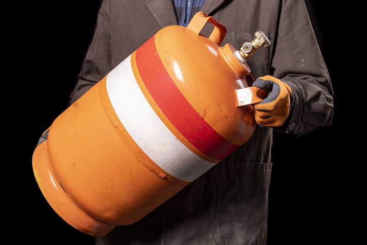 mężczyzna trzymający pomarańczową butlę gazową